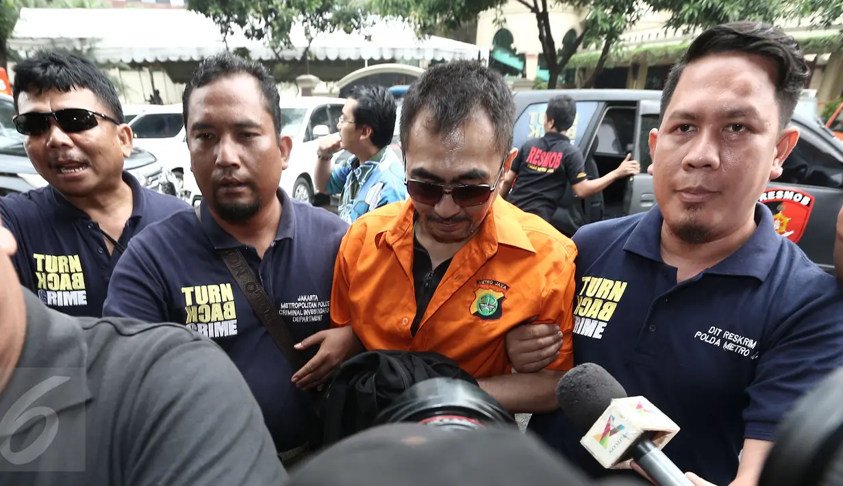 Mantan Ketua Parfi, Gatot Brajamusti dikawal petugas setibanya di Polda Metro Jaya, Jakarta, Jumat (21/10). Aa Gatot didatangkan dari Polda NTB ke Jakarta untuk menjalani pemeriksaan terkait rentetan kasus yang menjeratnya. (Liputan6.com/Herman Zakharia)
