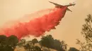 Pemadam kebakaran menggunakan pesawat membuang fire retardant untuk mengatasi kebakaran di Mariposa, California (19/7). Lebih dari 1.400 petugas pemadam kebakaran dikerahkan untuk menagatasi kebakaran tersebut. (AFP Photo/Josh Edelson)