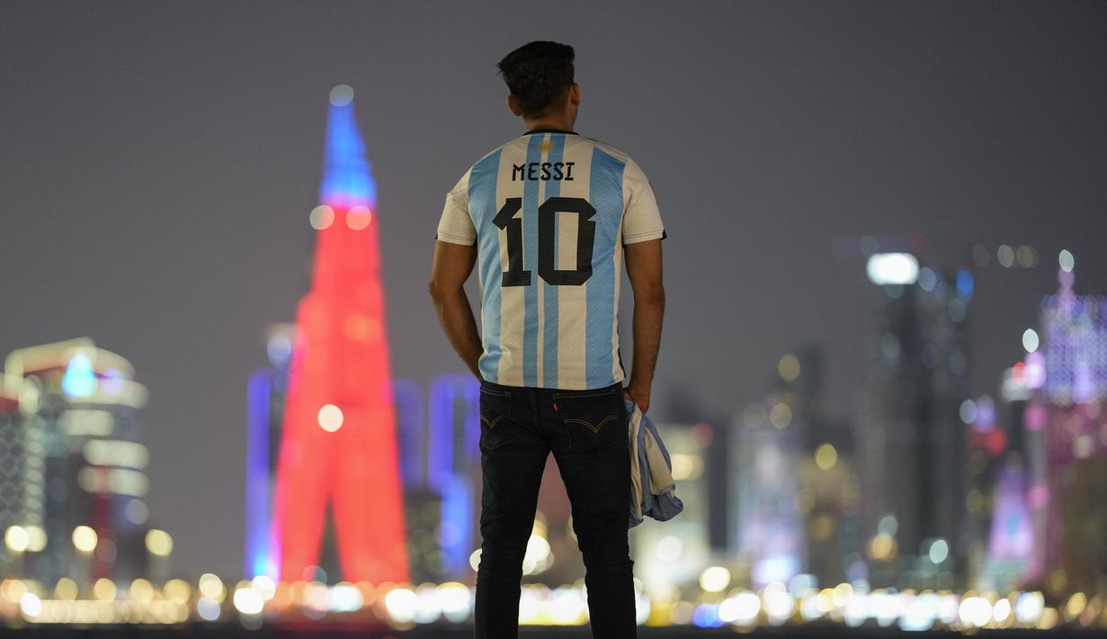 Seorang fans berdiri mengenakan kostum Argentina bertuliskan nama Messi di corniche Doha, di Doha, Qatar, Senin, 12 Desember 2022. Argentina akan menghadapi Kroasia dalam pertandingan semifinal Piala Dunia 2022 di Stadion Lusail Iconic Qatar, Rabu (14/12/2022) mulai pukul 02.00 WIB. (AP Photo/Andre Penner)