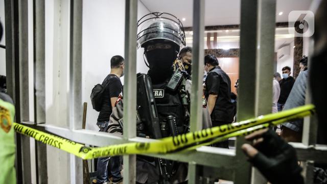 <span>Polisi berjaga saat penggeledahan di lokasi bekas Sekretariat Markas Front Pembela Islam di Petamburan, Jakarta, Selasa (27/4/2021). Munarman juga diduga menyembunyikan informasi tentang tindak pidana terorisme. (Liputan6.com/Faizal Fanani)</span>
