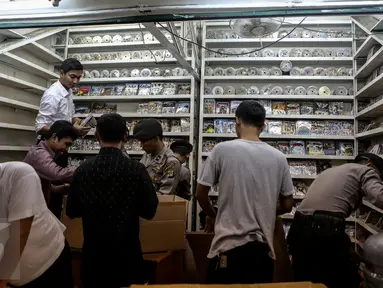 Petugas memeriksa tempat produksi VCD dan DVD bajakan di Plaza Glodok, Jakarta, Rabu (24/6). Penggerebekan dilakukan karena pabrik sekaligus tempat penjualan DVD terbesar di DKI Jakarta itu masih beroperasi selama Ramadan. (Liputan6.com/Faizal Fanani)