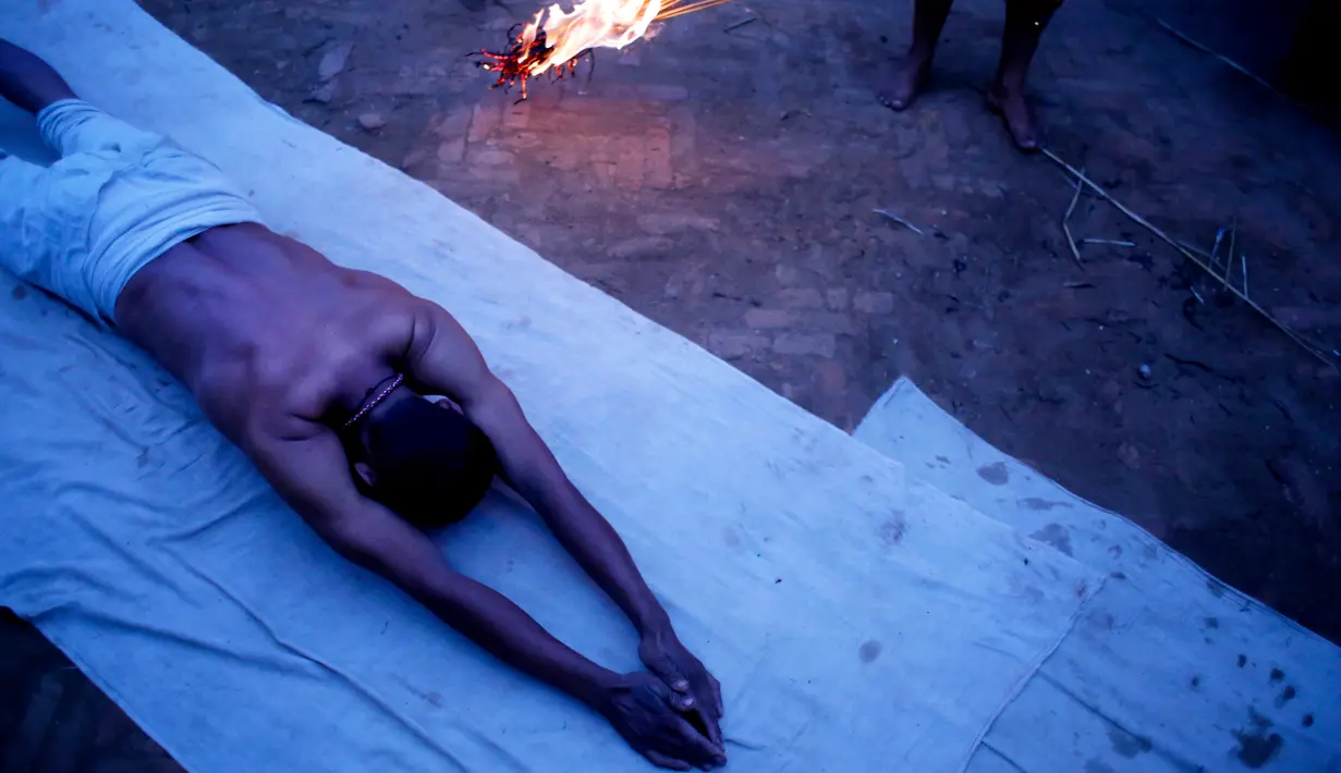 Seorang pria Hindu Nepal berguling di tepi sungai Hanumante saat festival Madhav Narayan di Bhaktapur, Nepal (31/1). Ritual ini untuk persembahan kepada Dewi Swasthani dan Dewa Siwa. (AP Photo / Niranjan Shrestha)
