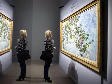 Refleksi dari cermin yang menggambarkan seorang wanita melihat lukisan Claude Monet 'The Roses' saat pameran 'Monet. Capolavori dal Musee Marmottan' di Roma, Italia (18/10). (Angelo Carconi / ANSA via AP)