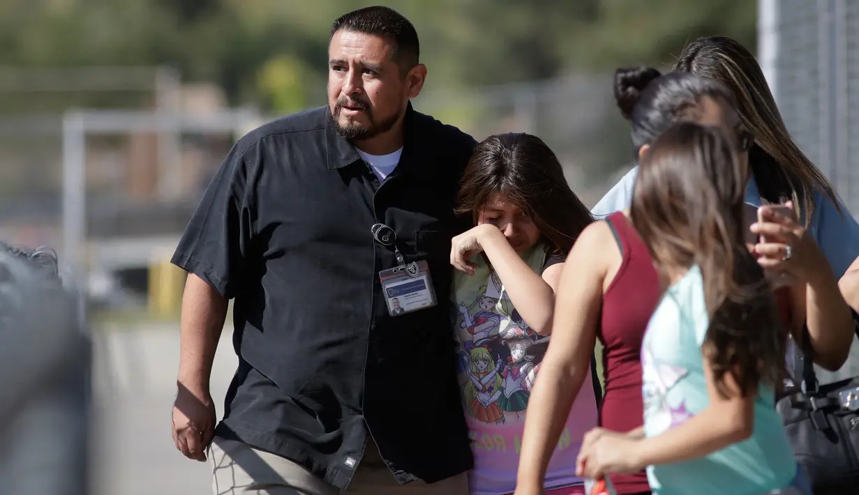 Camilo Rocha (kiri) menenangkan putrinya setelah insiden penembakan di Sekolah Dasar North Park, San Bernardino di California, Senin (10/4). Polisi menyebut aksi itu sebagai pembunuhan yang diikuti bunuh diri sang pelaku. (AP Photo/Jae C. Hong)