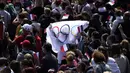 Fans membawa bendera di zona penggemar Olimpiade di Trocadero Gardens di depan Menara Eiffel di Paris, Minggu (8/8/2021). Pelepasan tongkat tuan rumah akan dibagi antara Stadion Olimpiade di Tokyo dan pesta publik dan konser di Paris. (AP Photo/Francois Mori)