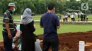 Sebagian kerabat menunggu giliran untuk berdoa di area pemakaman khusus dengan protokol COVID-19 di TPU Bambu Apus, Jakarta, Jumat (22/1/2021). Sejak dibuka Kamis (21/1) kemarin hingga hari ini, tercatat sekitar 35 jenazah dimakamkan dengan protokol COVID-19. (Liputan6.com/Helmi Fithriansyah)