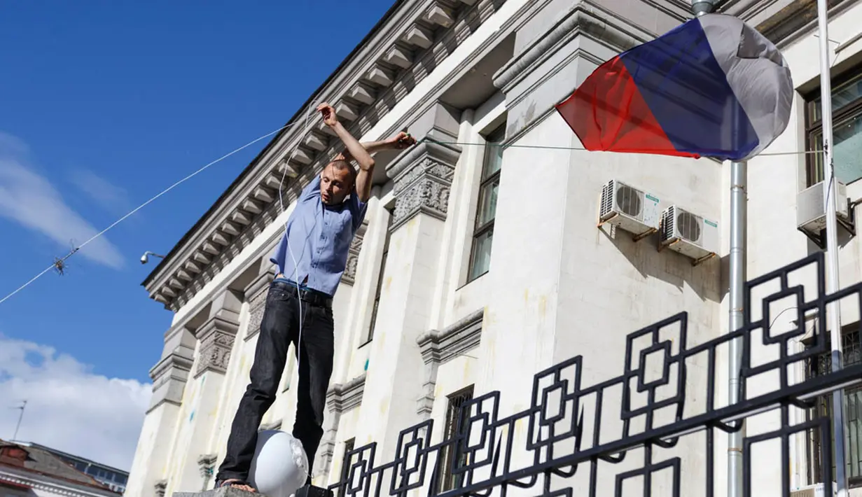 Massa aksi terlihat menurunkan bendera Rusia yang berkibar di halaman Kedutaan Besar di Kiev, Ukraina, (14/6/2014). (REUTERS/Oleg Pereverzev)