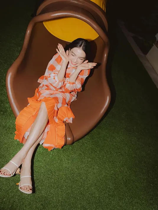 Raline Shah mengenakan two piece kotak-kotak oranye dari Danhyo Hiyoji. Terdiri dari kemeja baloon sleeve dan rok midi asimetris denggan outline ruffle [@ralineshah]