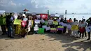 Massa mengangkat plakat saat kampanye perubahan iklim global di Pantai Sanur, Bali, Jumat (20/9/2019). Kampanye ini menuntut tindakan yang lebih cepat untuk mengatasi perubahan iklim global. (SONNY TUMBELAKA/AFP)