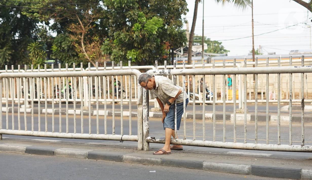 Warga menerobos celah pagar pembatas jalan di depan Stasiun Pasar Minggu, Jakarta, Rabu (16/10/2019). Jauhnya jembatan penyeberangan orang (JPO) membuat warga memanfaatkan celah pagar pembatas tersebut sebagai akses menyeberang, meski berbahaya bagi keselamatan. (Liputan6.com/Immanuel Antonius)