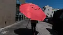 Seorang wanita berjalan dengan payung pantai di Los Angeles, Rabu, (31/8/2022). Peringatan panas berlebihan meluas ke seluruh California Selatan dan ke utara, beberapa kota California memecahkan rekor panas, naik setinggi 112F, dan kobaran api meletus saat penduduk terpaksa mengungsi. (AP Photo/Jae C.Hong)