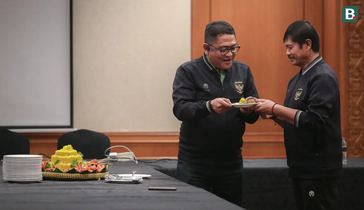 Anggota Exco PSSI yang sekaligus menjabat manajer tim, Endri Irawan memberikan potongan tumpeng kepada pelatih kepala Timnas Indonesia U-22, Indra Sjafri saat syukuran terkait sanksi ringan FIFA terhadap Indonesia dan kesempatan Timnas Indonesia U-22 tampil di SEA Games 2023 di Ruang Semeru, Hotel Sultan, Jakarta. (Bola.com/Bagaskara Lazuardi)