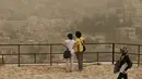 Wisatawan melihat pemandangan di Citadel Amman saat badai pasir berlangsung di kota Amman, Yordania, 8 September 2015. Badai pasir besar melanda Timur Tengah, menewaskan 2 orang dan ratusan orang dirawat di rumah sakit di Lebanon. (REUTERS/Muhammad Hamed)