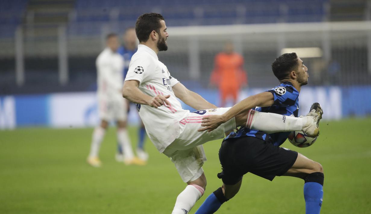 Bek Real Madrid, Nacho, berebut bola dengan bek Inter Milan, Achraf Hakimi, pada laga lanjutan Liga Champions di Giuseppe Meazza, Kamis (26/11/2020) dini hari WIB. Real Madrid menang 2-0 atas Inter Milan. (AP Photo/Luca Bruno)