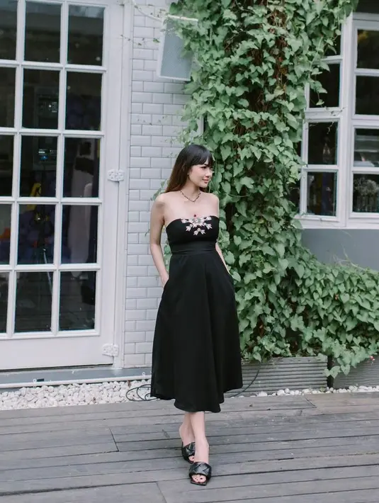Dia mengenakan strapless dress model a-line warna hitam dengan sandal slip on warna senada. (Instagram/adieztyfersa).