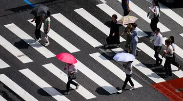 Pejalan kaki menggunakan payung saat menyeberangi jalan di Seoul pada tanggal 14 Agustus 2024. (Anthony WALLACE/AFP)