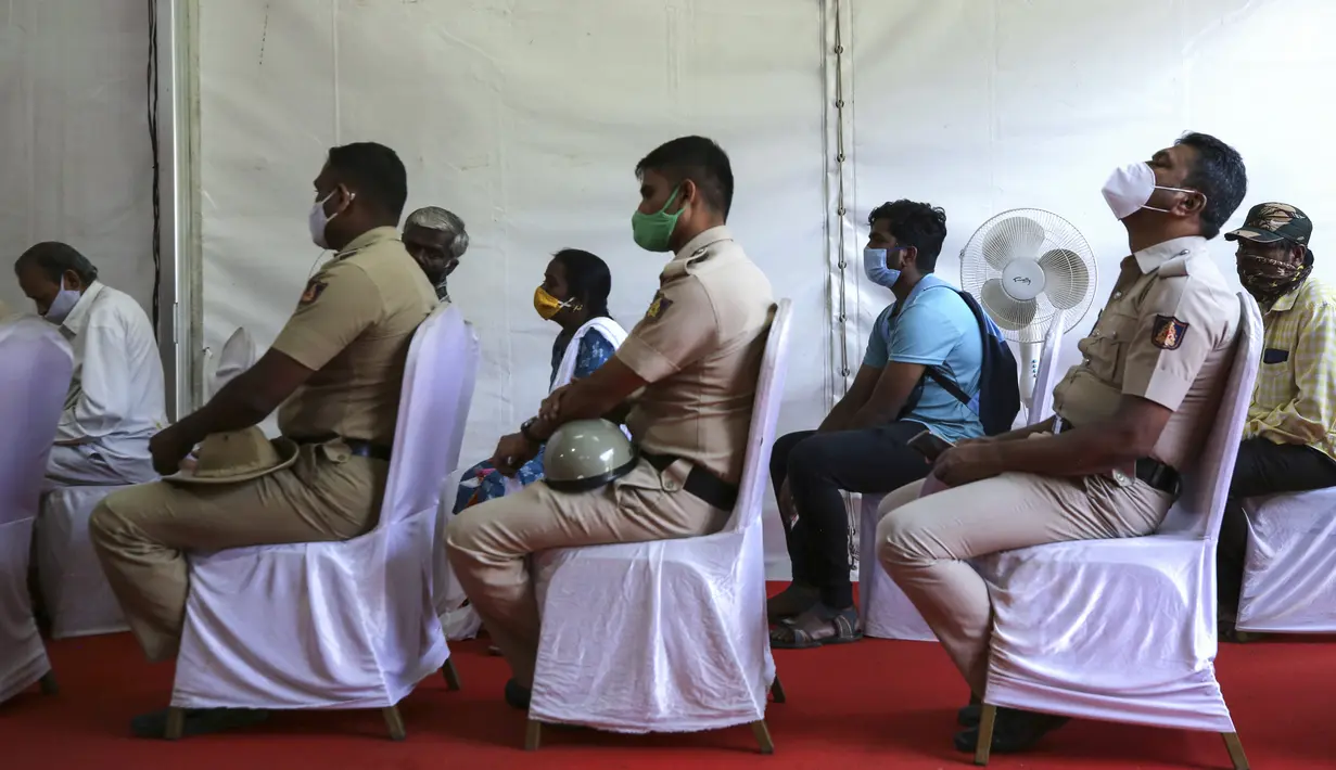 Polisi India menunggu bersama orang lain untuk menerima vaksin COVID-19 dosis ketiga di pusat vaksinasi di Bengaluru, India (10/1/2022). Penyebaran varian Omicron yang cepat telah memicu lonjakan kasus baru hingga delapan kali lipat sejak awal tahun. (AP Photo/Aijaz Rahi)