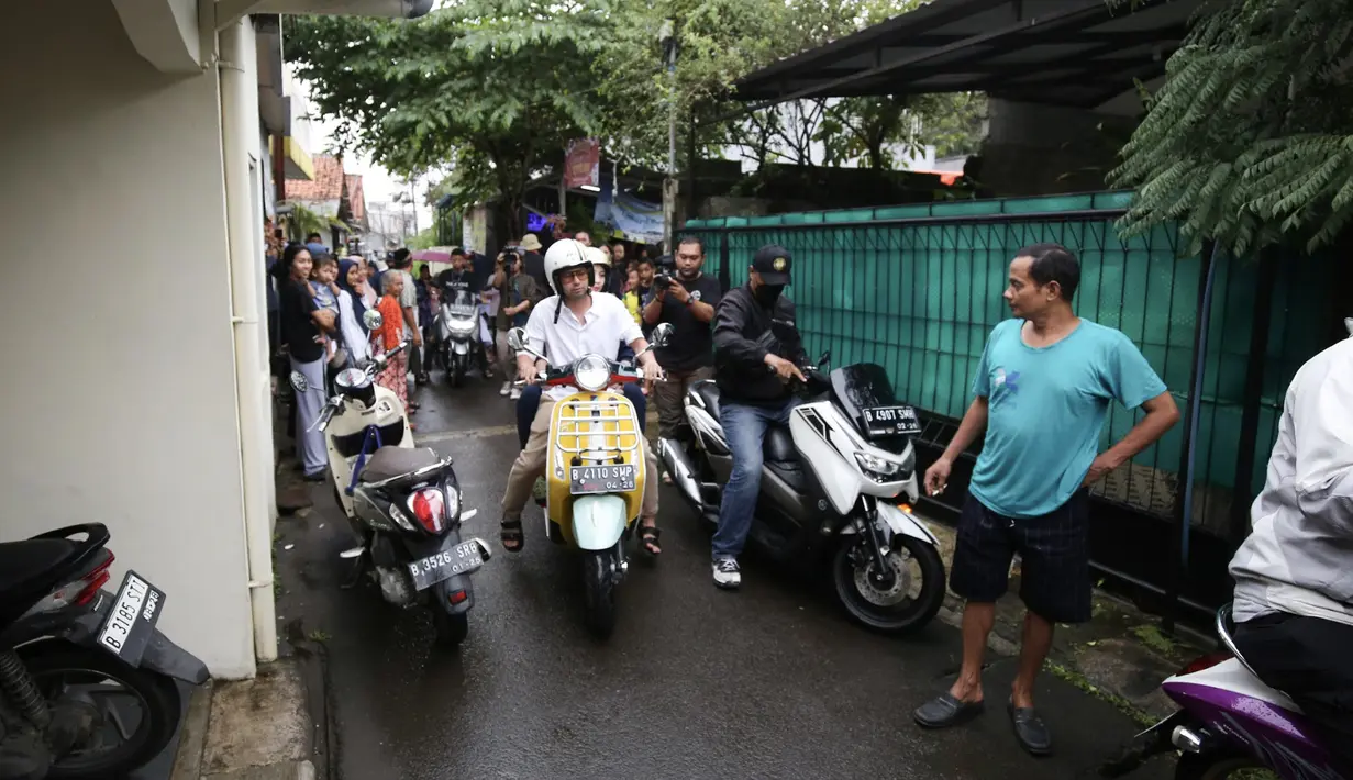 Raffi Ahmad mengenakan motor Vespa kuningnya. Ia tampak membonceng Nagita Slavina dan sama-sama memakai helm putih. [Foto: Bayu Herdi]