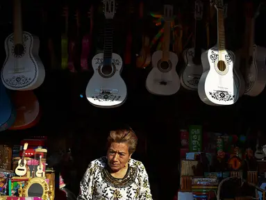 Seorang wanita menjual replika gitar dari film "Coco" di kiosnya di Paracho, Meksiko (8/1). Kerena kepopuleran film animasi Coco pengrajin di Meksiko dibanjiri pesanan gitar yang mirip di film tersebut. (AFP Photo/ Ronaldo Schemidt)
