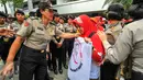 Seorang polwan berdialog dengan pendemo agar tidak menutup akses jalan ketika menggelar demonstrasi di depan gedung Kemenkes, Jakarta, Rabu (4/5). Para bidan desa berdemo menuntut diangkat menjadi pegawai tetap tanpa syarat.  (Liputan6.com/Yoppy Renato)