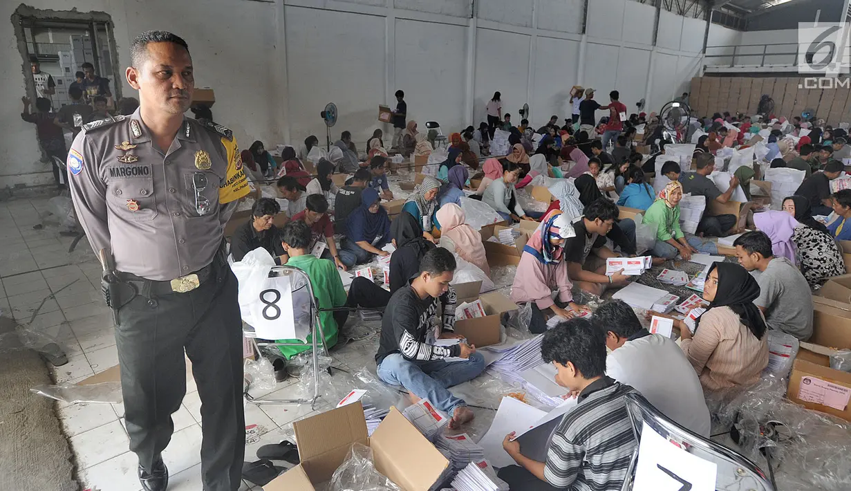Petugas kepolisian Babinkamtibmas Pabuaran Bogor mengawasi pelipatan kertas suara DPD RI di Gudang KPU, Bogor, Jawa Barat, Kamis (21/2). 650 relawan dilibatkan dalam penyortiran dan pelipatan kertas suara Pemilu 17 April 2019. (Merdeka.com/Arie Basuki)