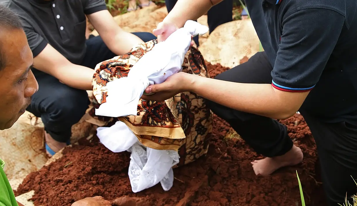 Jenazah anak ke-3 Bekti dan Dila, Kenward Athar Indrabekti, dimasukan ke dalam liang lahat oleh ayahnya sendiri. Melakukan prosesi tersebut, Bekti tampak menahan rasa sedihnya. (Bambang E. Ros/Bintang.com)
