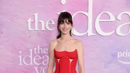 Anne Hathaway tampil memukau dalam balutan gaun merah dengan potongan dan memadukannya dengan anting-anting berlian. (KENA BETANCUR / AFP)