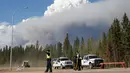 Petugas berjaga di kawasan dekat dari kepulan asap yang membakar hutan di wilayah Fort McMurray, Alberta, Kanda, 4 Mei 2016. Kebakaran ini merupakan yang terbesar kedua di wilayah tersebut dalam setahun. (REUTERS / Topher Seguin)