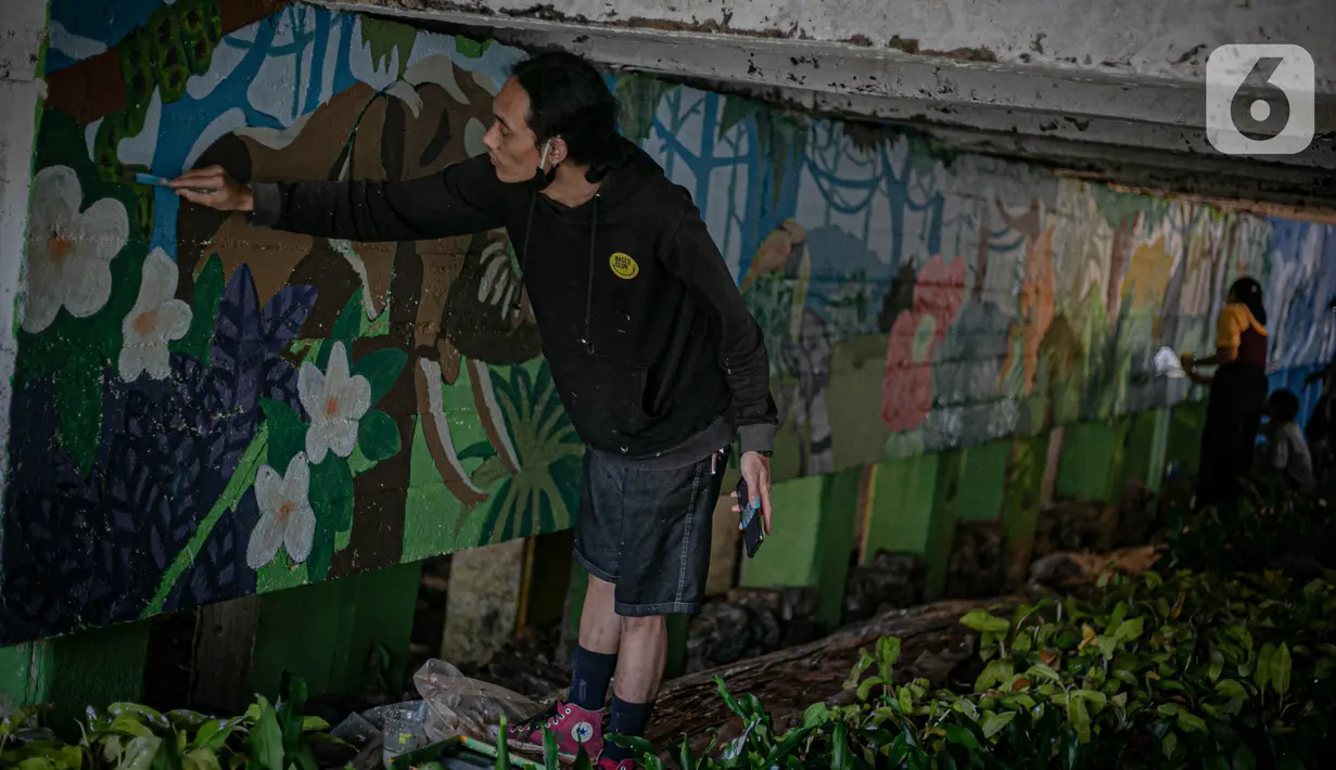 Mahasiswa Institut Kesenian Jakarta (IKJ) menyelesaikan pembuatan mural di kolong Jembatan Pegangsaan, Menteng, Jakarta, Selasa (26/1/2021). Pembuatan mural tersebut bertujuan mempercantik kawasan bantaran kali dan sebagai ruang interaksi warga. (Liputan6.com/Faizal Fanani)