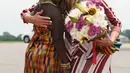 First Lady AS, Melania Trump memeluk seorang anak perempuan berpakaian tradisional Ghana setibanya di Bandara Kotoka di Accra, Selasa (2/10). Melania juga mendapatkan buket bunga yang diletakkan dalam keranjang anyaman warna-warni. (AP/Carolyn Kaster)