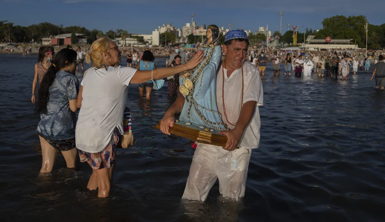 Seorang wanita menyentuh patung dewi laut Afrika Yemanja saat ia berpartisipasi di Pantai Ramirez di Montevideo, Uruguay, Rabu (2/2/2022). Para pemuja mendatangi pantai pada pada hari raya Yemanja, membawa lilin, bunga, madu dan buah untuk menghormati dewi laut. (AP Photo/Matilde Campodonico)