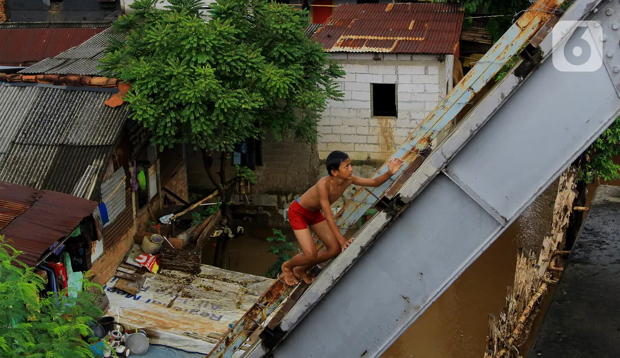 Seorang anak menaiki jembatan sebelum melakukan aksi lompat di Jembatan Ciliwung Kalibata, Jakarta, Selasa (25/2/2020). Beberapa anak nekat bermain air dengan lompat dari atas jembatan Ciliwung Kalibata, Jakarta, Selasa (25/2/2020). (merdeka.com/magang/Muhammad Fayyadh)