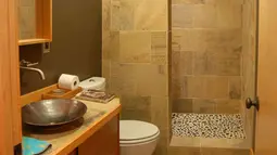 Hadirkan suasana alami ke dalam kamar mandi dengan penggunaan material batu alam, baik yang alami maupun buatan. Paduan nuansa alam dengan gemericik air akan membuat mandi terasa lebih segar. Foto: Cyclonic Traffic