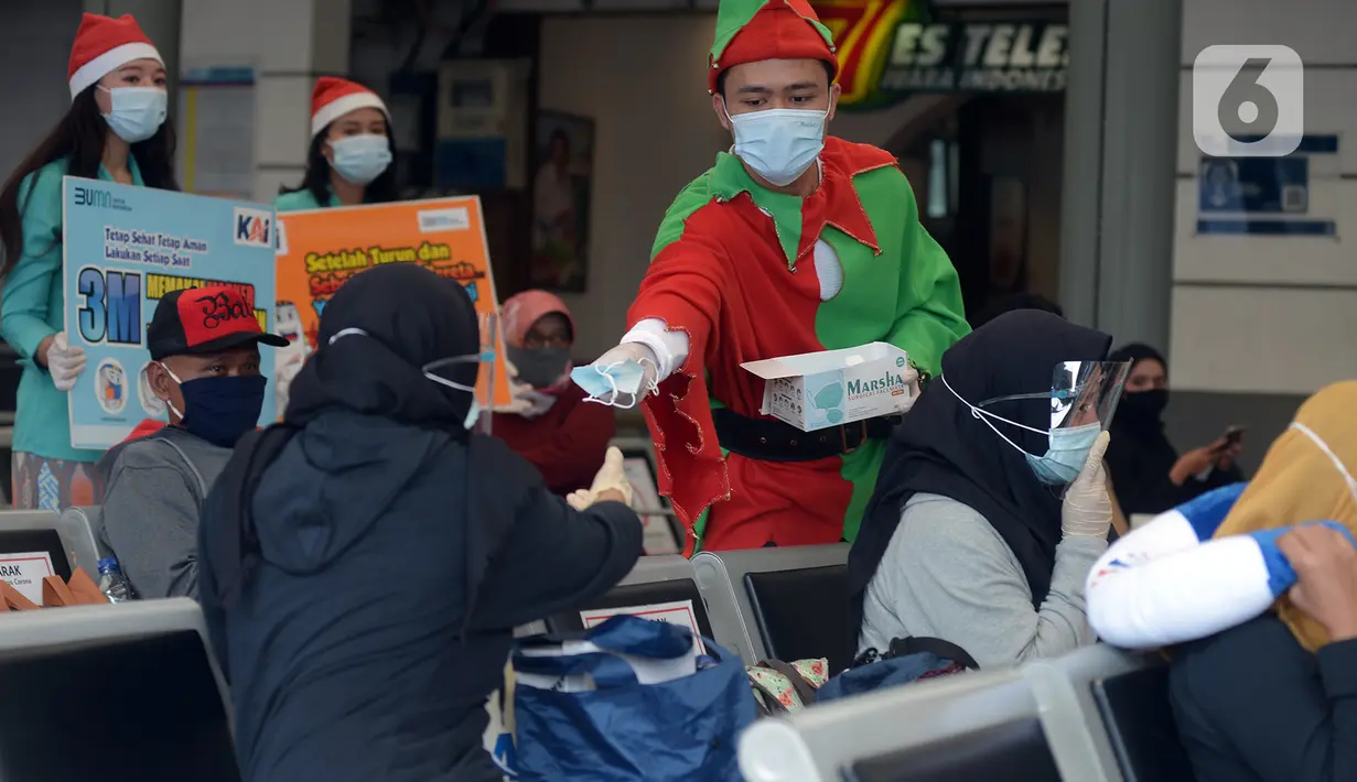 Petugas KAI yang mengenakan kostum Natal membagikan masker kepada calon penumpang di Stasiun Senen, Jakarta, Jumat (25/12/2020). Pembagian ini dilakukan untuk mengganti masker yang sudah dipakai calon penumpang selama perjalanan. (merdeka.com/Imam Buhori)