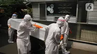 Petugas pemulasaraan jenazah Covid-19 membawa peti jenazah yang meninggal ketika menjalani isolasi mandiri di Kampung Gedong, Jakarta, Sabtu (10/7/2021). Proses pemulasaran jenazah dilakukan sesuai prokes Covid-19 dikarenakan hasil test swab korban positif. (merdeka.com/Imam Buhori)