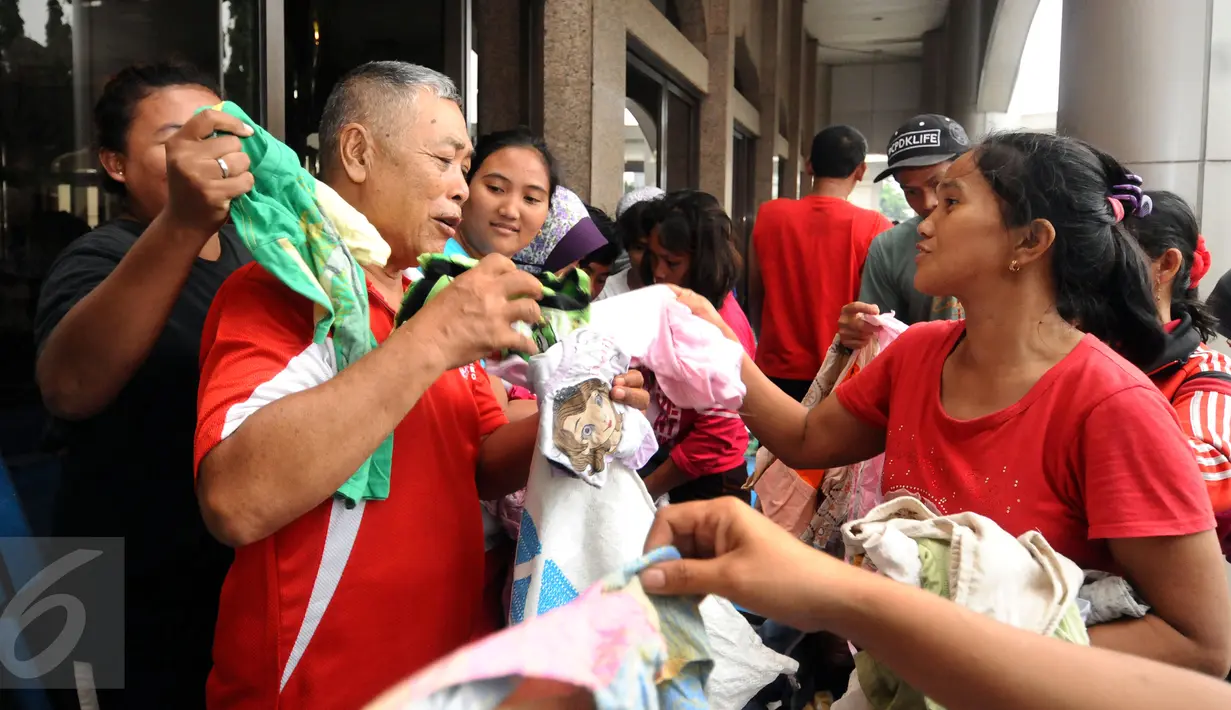 Beberapa warga berebut pakaian layak pakai di pelataran Masjid Raya Universitas Borobudur, Jakarta, Senin (20/2). Ratusan warga Cipinang Melayu terpaksa mengungsi akibat banjir yang menggenangi pemukiman mereka. (Liputan6.com/Helmi Fithriansyah)