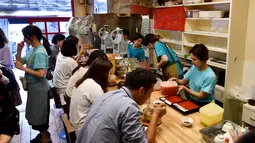 Pelanggan menikmati kakigori atau es serut di distrik Yanaka Tokyo, Jepang (21/6/2019). makanan penutup musim panas yang menyegarkan ini terbuat dari campuran es serut, sirup buah dan susu kental manis. (AFP Photo/Toshifumi Kitamura)