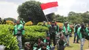 Seorang pengemudi ojek online membawa bendera merah putih saat melakukan aksi di seberang Istana Merdeka, Jakarta, Selasa (27/3). Mereka juga meminta legalitas angkutan ojek online. (Liputan6.com/Arya Manggala)