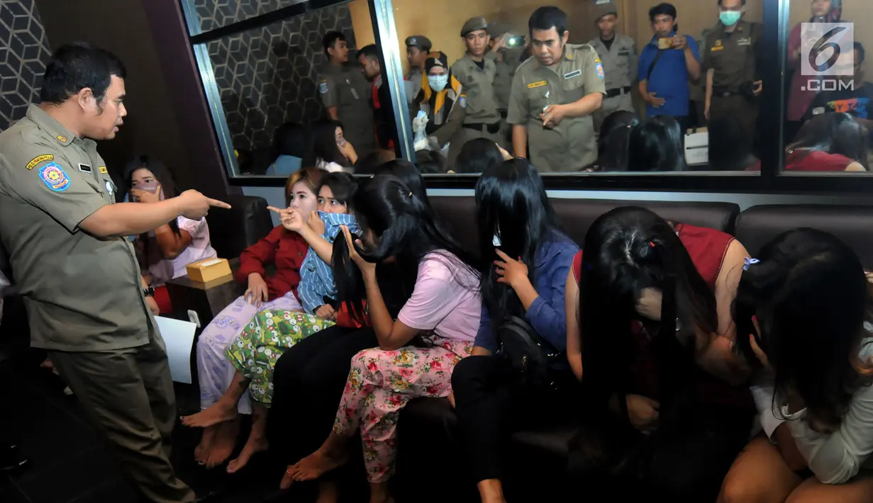 Petugas Satpol PP mengintrogasi sejumlah wanita selama razia panti pijat di BSD, Tangerang Selatan, Selasa (25/6/2019). Dalam razia tersebut puluhan wanita diamankan karena tidak bisa menunjukan kartu identitas. (merdeka.com/Arie Basuki)