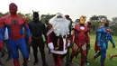 Sejumlah pria mengenakan kostum pahlawan super berjalan di istana kepresidenan di Pantai Gading (23/12). Mereka mengenakan kostum pahlawan super sambil membawa hadiah yang diberikan kepada anak-anak untuk perayaan natal. (AFP Photo/Sia Kambou)