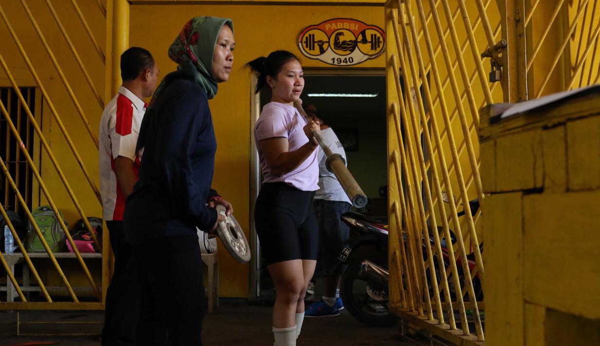 Atlet Angkat Besi Indonesia mengangkut peralatan untuk berlatih dekat halaman Parkir Angkat Besi di Senayan, Jakarta, Senin (11/1/2016). Hal ini karena tempat Latihan dalam tahap renovasi. (Bola.com/Nicklas Hanoatubun)