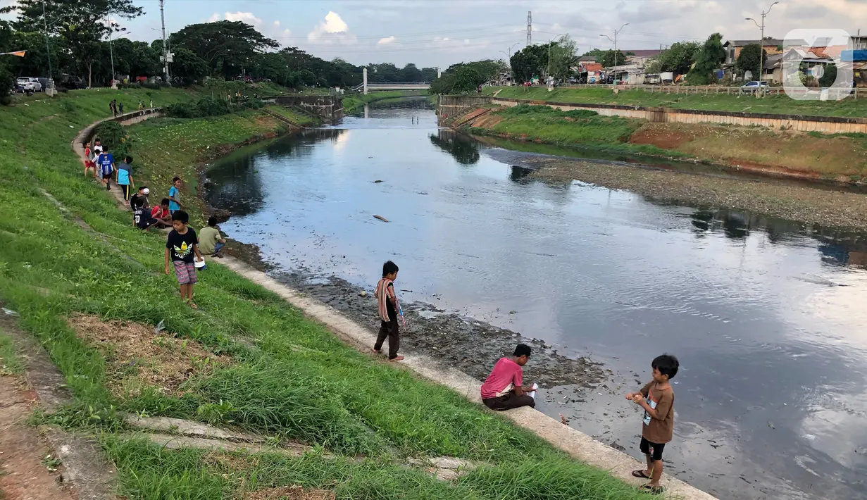 Anak-anak bermain di sekitar bantaran Kanal Banjir Timur (KBT), kawasan Cipinang Muara, Jakarta, Selasa (16/6/2020). Sebagian besar warga masih mengabaikan protokol kesehatan dengan tidak menjaga jarak serta tanpa menggunakan masker. (Liputan6.com/Immanuel Antonius)