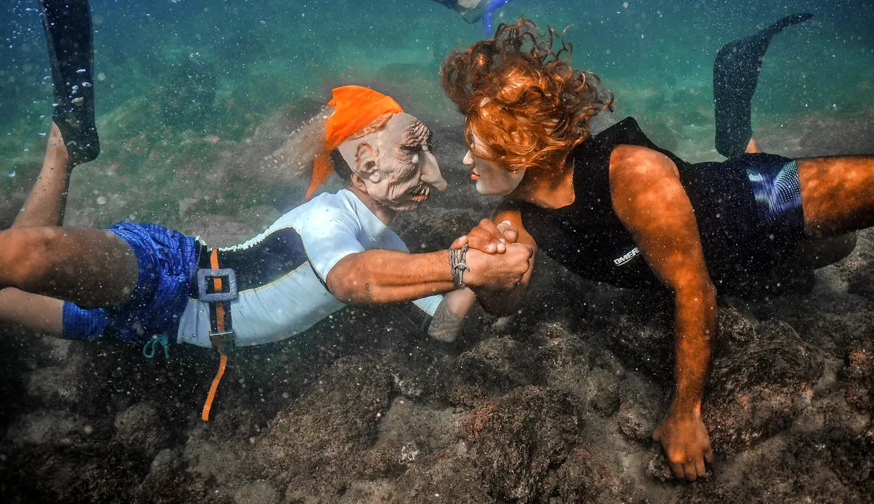 Orang-orang yang mengenakan kostum Halloween berinteraksi saat berenang di sepanjang pantai kota Batroun, Lebanon utara, Kamis (28/10/2021). Setiap tanggal 31 Oktober berbagai orang di belahan dunia biasa merayakan Halloween, hari yang identik dengan horor dan hal menakutkan. (Ibrahim Chalhoub/AFP)