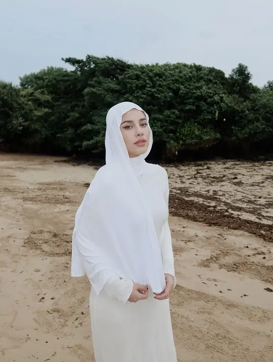 Berpose sendiri di pantai pasir putih, Aghnia Punjabi tampil simpel dengan atasan dan celana putih, dan hijab putih polos. [Foto: Instagram/emyaghnia]