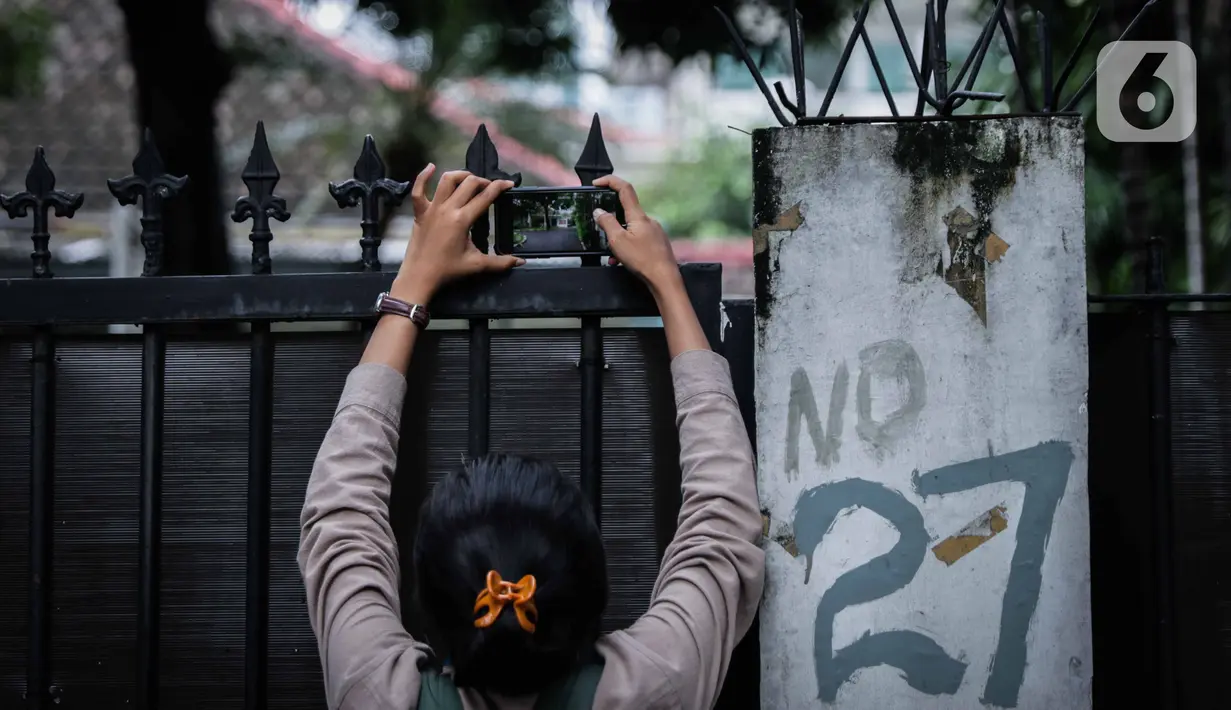 Seorang perempuan mengambil gambar kondisi gedung sementara tempat para komisioner KPU bekerja, tepat di sebelah Kantor KPU Pusat, Jakarta, Kamis (9/1/2020). KPK menyegel ruang kerja Komisioner KPU RI, Wahyu Setiawan pada Kamis pagi setelah OTT KPK. (Liputan6.com/Faizal Fanani)