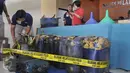 Petugas menata barang bukti saat rilis kasus pencurian solar di Polres Pelabuhan Tanjung Priok, Jakarta Utara, Selasa (29/12). Aksi tersebut dilakukan dari 2009 di wilayah Pertamina Digul Pelabuhan Tanjung Priok. (Liputan6.com/Gempur M Surya)