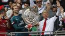 Arsene Wenger (kanan) akhirnya mengangkat trofi juara setelah timnya mengalahkan Chelsea lewat adu penalti 4-1 pada Community Shield 2017  di Wembley Stadium, London, (6/8/2017). (AFP/Frank Augstein)