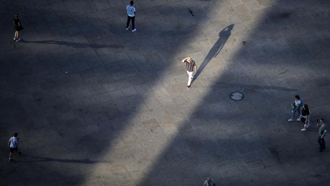 Seorang pria berjalan di bawah sinar matahari sore sambal melintasi pejalan kaki Alexanderplatz di Berlin, Jerman, 17 Agustus 2020. (Christoph Soeder / dpa via AP)