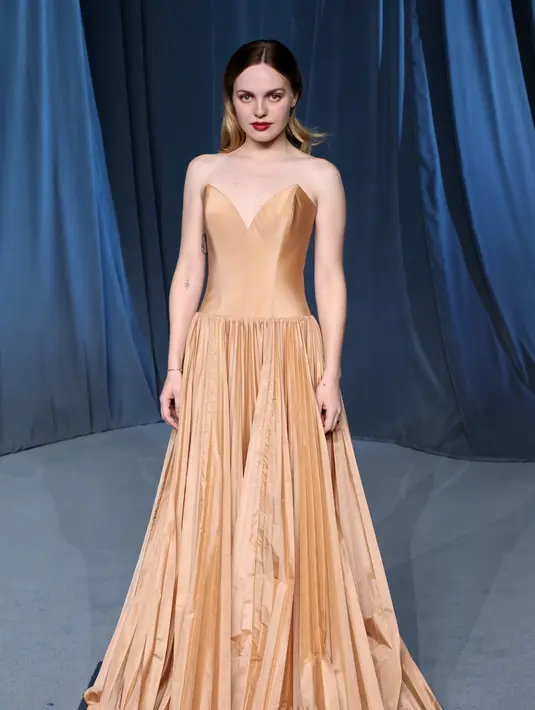 Aktris Odessa Young menutup daftar penampilan dengan aura romantis dalam gaun tanpa tali berwarna pinky sand dari bahan satin sutra dan detail tonal plissé pada bagian rok. Sepatu hak perak metalik menambah kilau penampilannya, sementara gelang emas kuning berhiaskan berlian dan anting stud berlian dari koleksi Louis Vuitton Fine Jewelry memberikan sentuhan akhir yang sempurna. [Dok/Louis Vuitton].