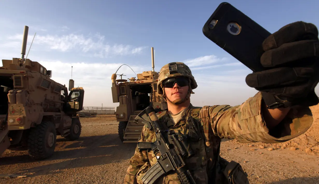 Seorang tentara Amerika Serikat berselfie di dekat kendaraan tempur di pangkalan militer AS di Qayyara, selatan Mosul (25/10). (REUTERS/Alaa Al-Marjani)